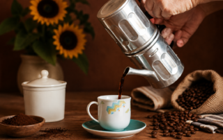 Mano che versa il caffè da una caffettiera napoletana tradizionale in una tazzina durante la preparazione del caffè